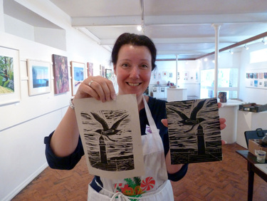 Picture of me and my lino print of a seagull wearing a scarf flying over Smeatons' Pier in St Ives